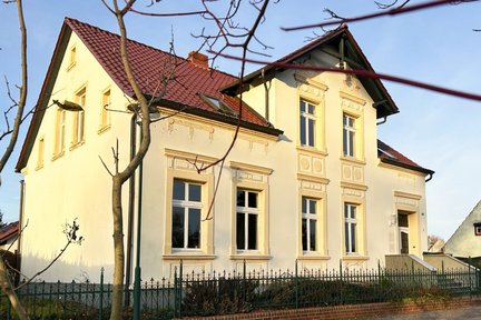 Fotoquelle: Gerrit van Doorn zeigt hell verputztes Gebäude mit abgesetzten Stuckverzierungen um Fenster und Tür